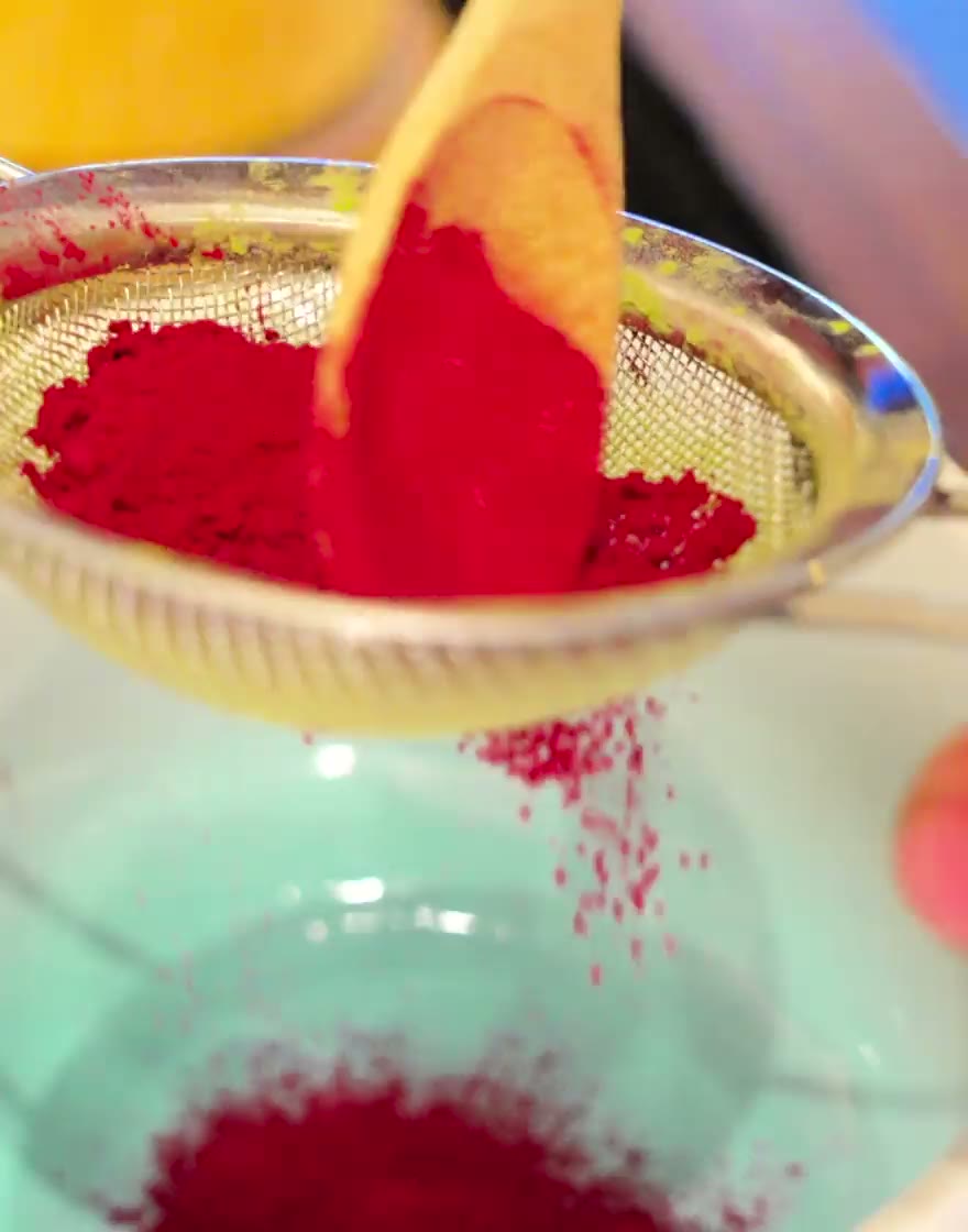 Raspberry powder sifted through a sieve into a matcha latte